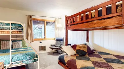 a bedroom with two bunk beds and a chair at Lakeview Villas #28 condo in Mammoth Lakes