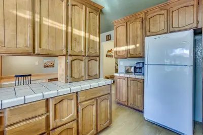 a kitchen with wooden cabinets and a white refrigerator at Pet-Friendly Escape with Game Room and Fire Pit! in North Fork