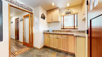 a kitchen with wooden cabinets and a door to a hallway at Mammoth Sierra Townhomes #18 condo in Mammoth Lakes