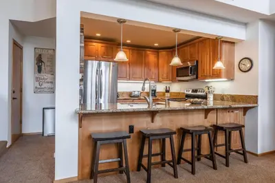 a kitchen with wooden cabinets and a bar with stools at Updated 3 Bedroom 3 Bathroom Snowcreek Phase V #884, Sleeps 6 in Mammoth Lakes