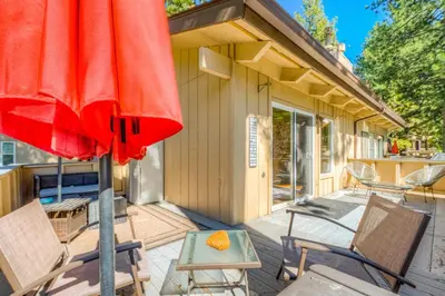 a patio with a red umbrella and chairs and a table at Incline Village Charmer in Incline Village