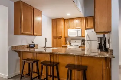 a kitchen with wooden cabinets and a counter with stools at Horizons IV 180 New Luxurious Listing Fully Remodeled 2 Bedrm Plus Loft 2 and a half Bathrm Sleeps 8 in Mammoth Lakes