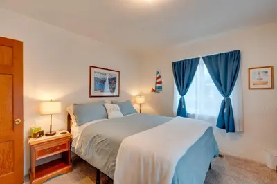 a bedroom with a bed and a window with blue curtains at Game Room and Patio Charming Jackson Retreat! in Jackson