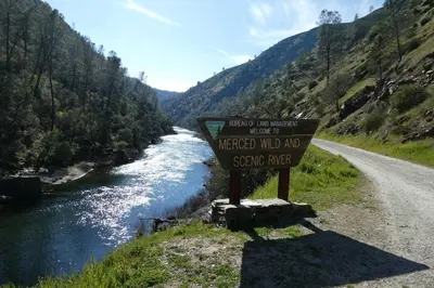 a sign on the side of a road next to a river at Foothill Acres in Midpines