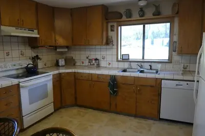 a kitchen with wooden cabinets and a sink and a window at Foothill Acres in Midpines