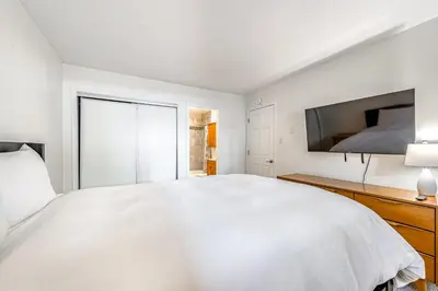 a white bedroom with a large bed and a flat screen tv at Take Me to Tahoe in Incline Village