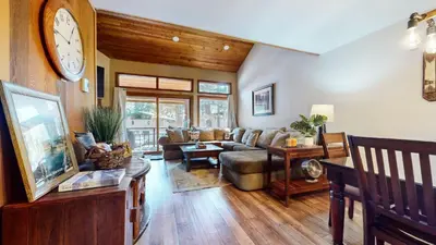 a living room with a couch and a clock on the wall at Woodlands #11 condo in Mammoth Lakes