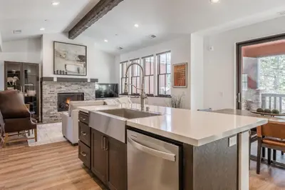a kitchen with a sink and a living room at Creekhouse 1553 in Mammoth Lakes