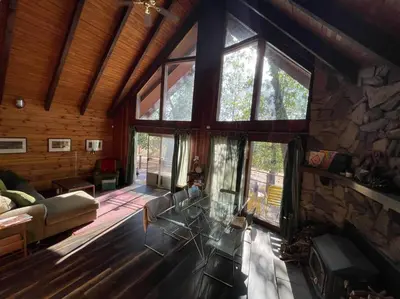 a living room with a glass table and a stone fireplace at Megans Mountain Getaway in Miramonte