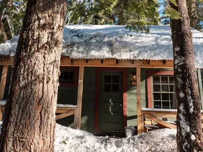 a cabin with a snow covered roof in the woods at Lakeshore Resort in Lakeshore