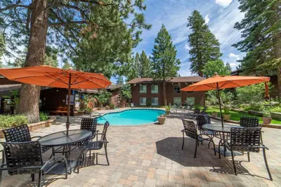 a patio with tables and umbrellas and a pool at Mammoth Estates 210 in Mammoth Lakes