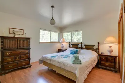a bedroom with a bed and a dresser and two windows at 7 Mi to Yosemite Natl Park Riverfront Getaway! in Groveland