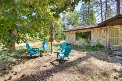 three blue chairs and an umbrella in front of a house at 7 Mi to Yosemite Natl Park Riverfront Getaway! in Groveland