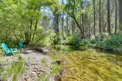 two blue chairs sitting next to a river at 7 Mi to Yosemite Natl Park Riverfront Getaway! in Groveland
