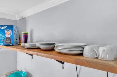 a wooden shelf with plates and cups on it at A Cottage - Walk to UC Davis & Shriners in Sacramento