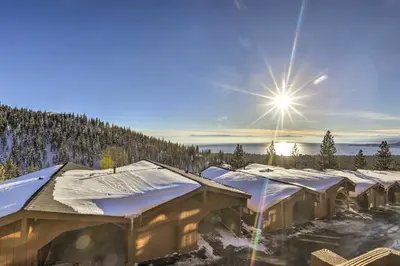 a row of snow covered buildings with the sun in the sky at Steps to Diamond Peak Incline Village Condo in Incline Village