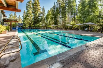 a swimming pool with blue water and trees at Northstar's Cozy Condo in Truckee