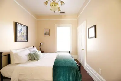 a bedroom with a bed with a chandelier and a window at A+ 2 BR Victorian Home away from Home in Sacramento