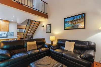 a living room with a leather couch and a staircase at Lake Tahoe Leisure in Carnelian Bay