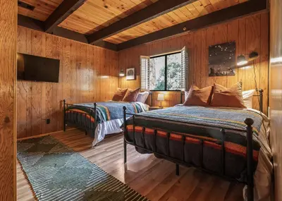 two beds in a room with wooden walls at Hygge Haus Sequoia - Large Private Cabin w Views in Ponderosa