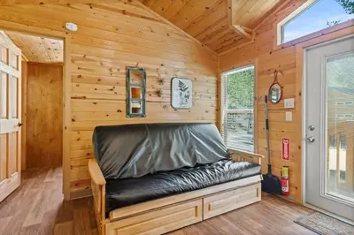 a black leather couch in a wooden room with a window at Quiet little pet friendly cabin in Kernville