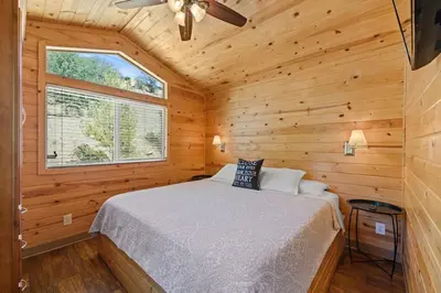 a bedroom with a bed in a wooden cabin at Deluxe little cabin 2 min stroll to Kern River in Kernville