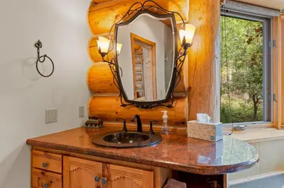 a bathroom with a sink and a mirror at Willow Cove Log Cabin in Bass Lake
