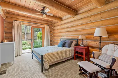 a log cabin bedroom with a bed and a chair at Willow Cove Log Cabin in Bass Lake