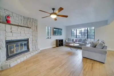 a living room with a stone fireplace and a ceiling fan at Pet-Friendly Hollister Getaway with Grill! in Hollister