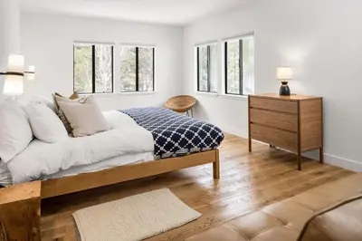 a bedroom with a bed and a dresser and windows at Desolation Hotel Hope Valley in Markleeville