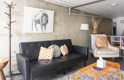 a living room with a black couch and a chair at Modern lofty studio in Midtown / Charming Old SW in Reno