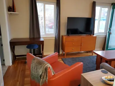 a living room with a tv and a orange chair at Midcentury Gem in Midtown Reno in Reno