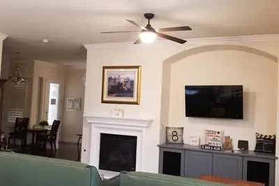 a living room with a ceiling fan and a fireplace at Chateau Sunnyside in Fresno