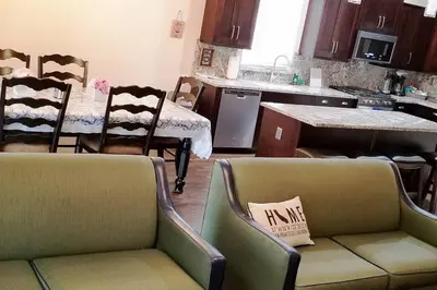 a living room with two chairs and a kitchen at Chateau Sunnyside in Fresno