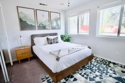a bedroom with a bed with white sheets and windows at Mountain Escape, Yosemite South Gate House with Hot Tub, Views & Game Room, Near town in Oakhurst