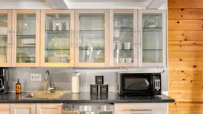 a kitchen with wooden cabinets and a microwave at Chickadee by AvantStay Modern A-Frame Cabin in Tahoe City