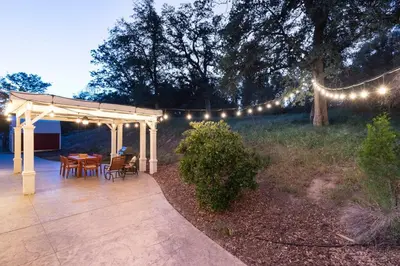 a patio with a table and chairs and lights at Relax at Yosemite, Cozy House with King Bed, Private Hot Tub & Fast Wi-Fi, Near town in Oakhurst