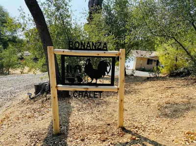 a sign with a chicken on it in a field at Relax at Yosemite, Cozy House with King Bed, Private Hot Tub & Fast Wi-Fi, Near town in Oakhurst
