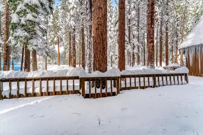 a wooden fence covered in snow in a forest at Fairway Forest in Incline Village