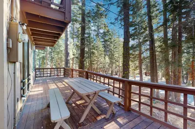 a wooden deck with a picnic table and benches at Talmont Trailhead Cabin in Tahoe City