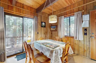a dining room with a table and some windows at Talmont Trailhead Cabin in Tahoe City