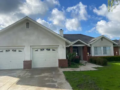 a house with white garage doors in a yard at Beautiful peaceful desirable home in Madera Rancho in Madera