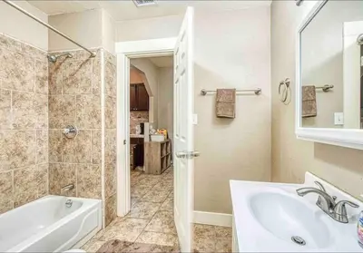 a bathroom with a tub and a sink and a mirror at 2 King Beds! Fantastic Stylish Bungalow home! in Fresno