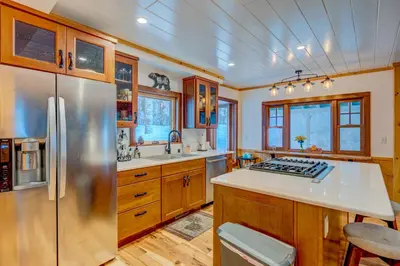 a kitchen with a stainless steel refrigerator and wooden cabinets at A Bear's Rest in Homewood