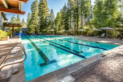 a swimming pool with blue water and trees at The Pines at Rocky Point in Truckee