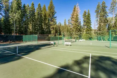 a tennis court with two benches on it at The Pines at Rocky Point in Truckee