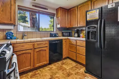 a kitchen with wooden cabinets and a black refrigerator at Minutes From Heavenly Valley & Lake Tahoe Beaches in South Lake Tahoe
