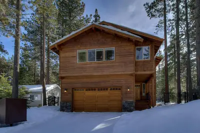 a wooden house with a garage in the snow at Brand New Upscale Home, Hot Tub, Foosball in South Lake Tahoe
