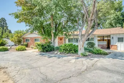 a brick house with trees in front of it at X-Large Spacious Deluxe House Fastest Wi-Fi in Fresno