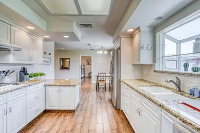 a kitchen with white cabinets and a hardwood floor at X-Large Spacious Deluxe House Fastest Wi-Fi in Fresno